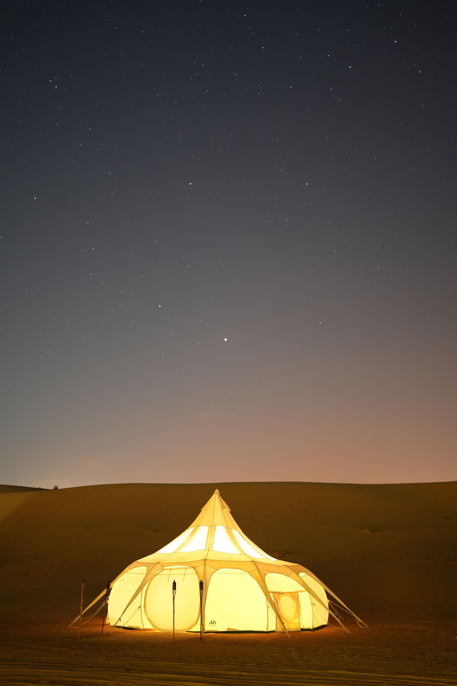 Glowing luxury tent in the Dubai desert under a starry night sky