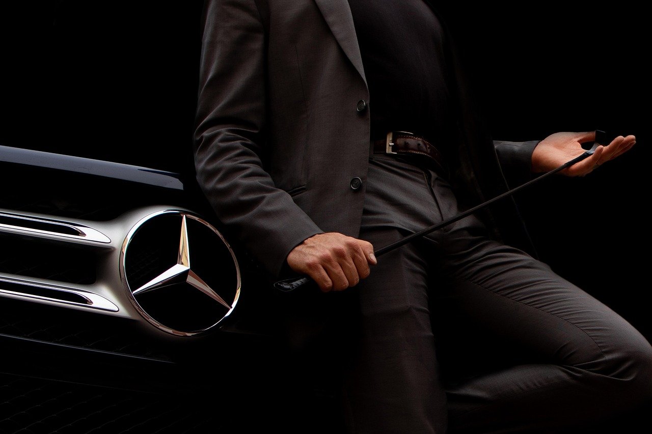 Chauffeur beside a Mercedes at night